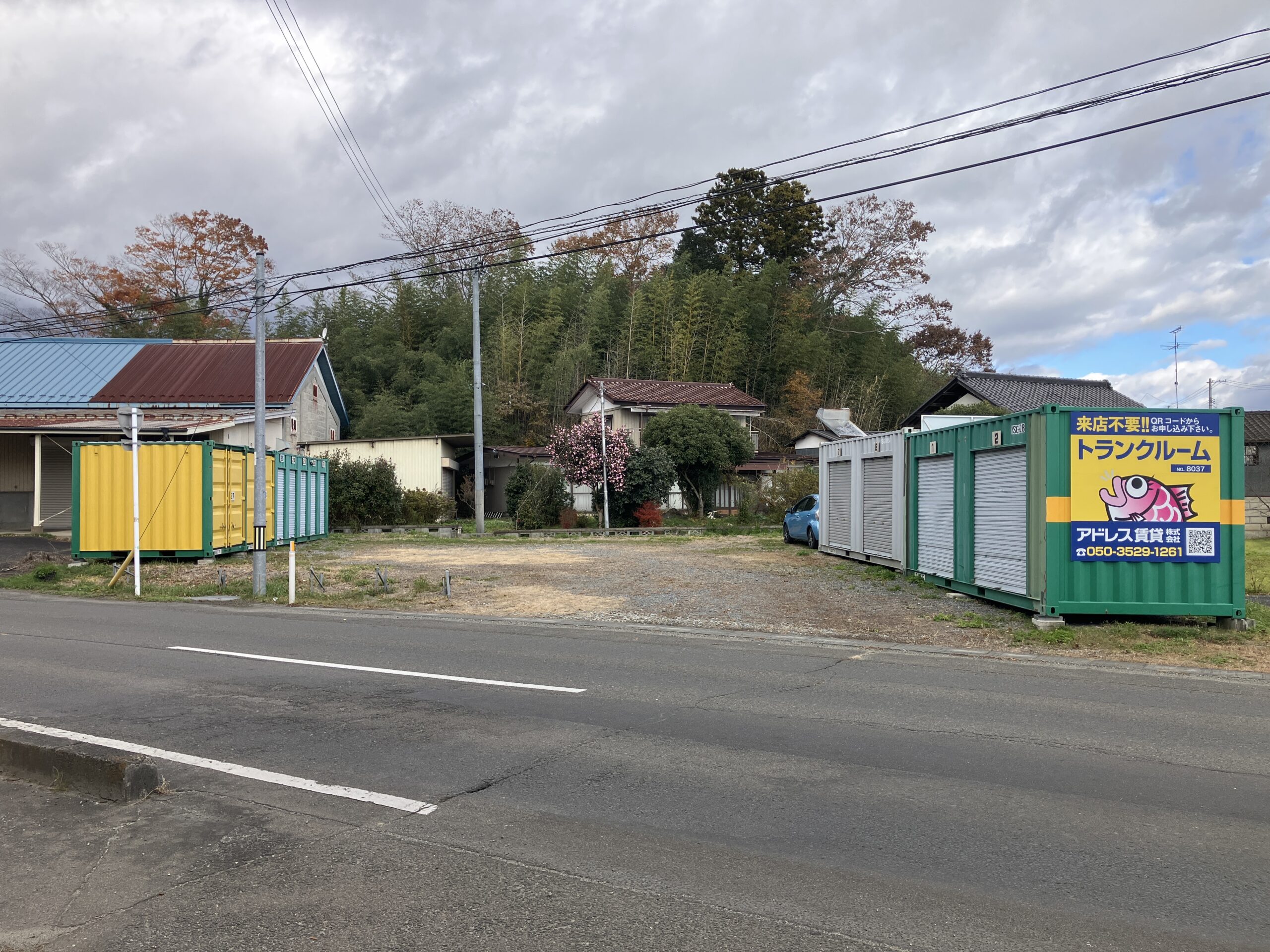屋外に並んだコンテナ型トランクルームの前にトラックを横付けし、デスクや椅子を運び込む作業員