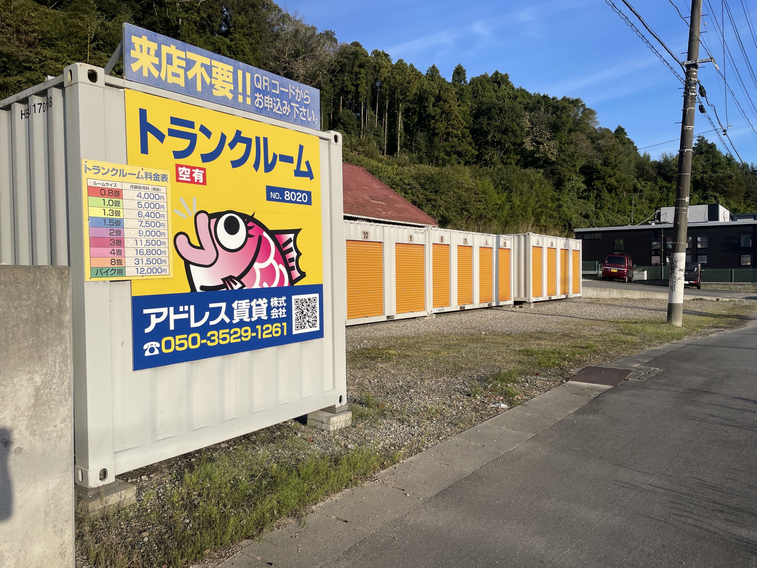 屋外に並んだコンテナ型トランクルームの前に車を横付けし、家具を運び込むシニア男性と手伝う家族