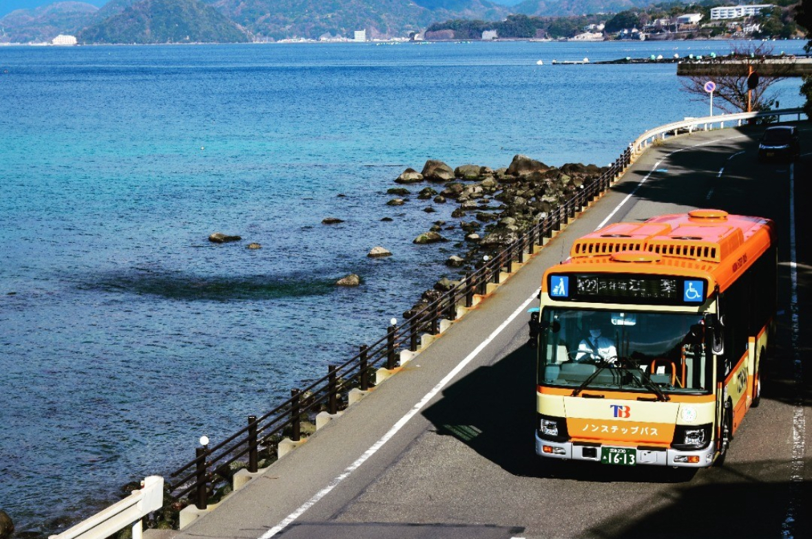 伊豆半島の海沿いの道路を走る路線バスと、車窓から見える穏やかな海の風景