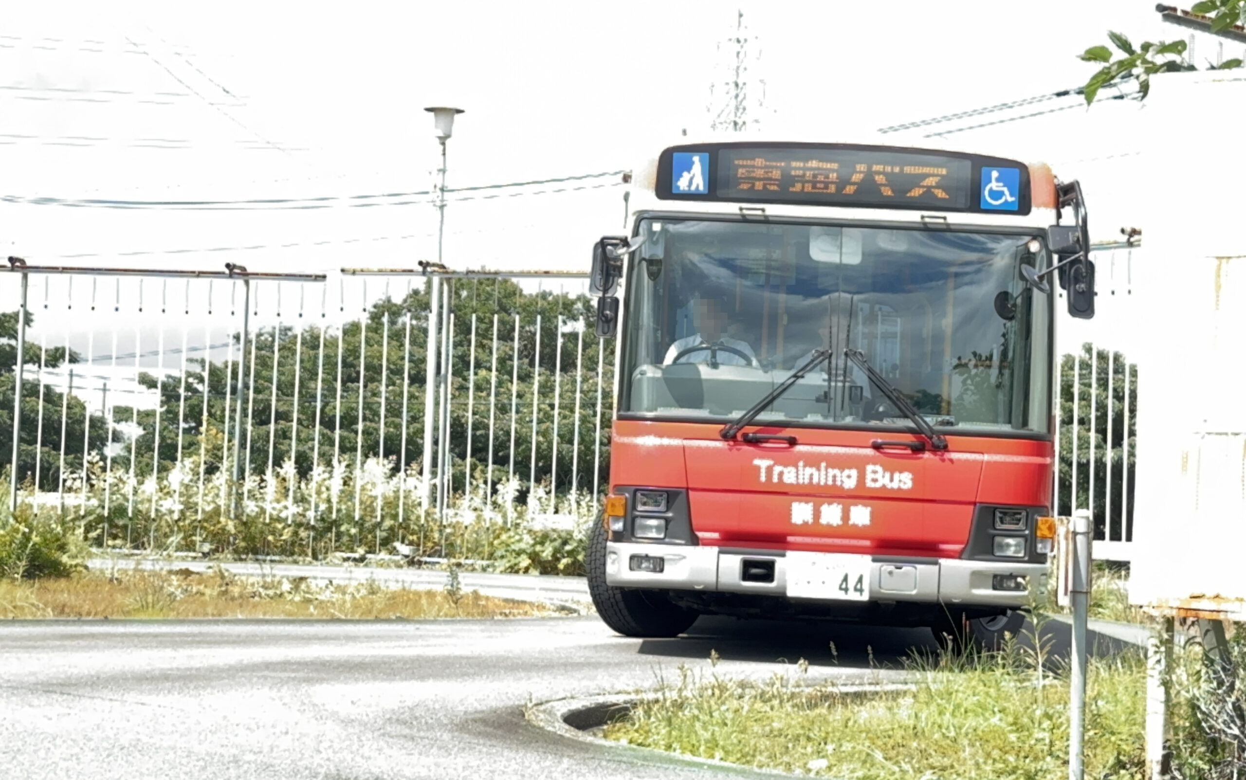 東海バスの運転体験会で実際のバスの運転席に座り、笑顔でハンドルを握る参加者と横で見守る指導員