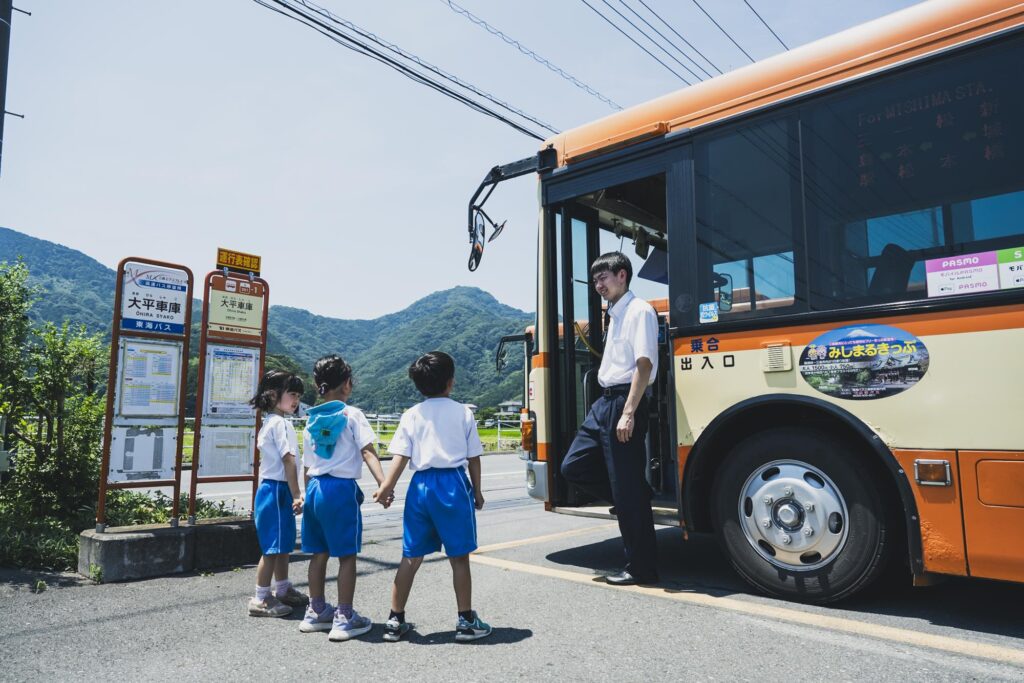富士山を背景に伊豆の美しい海岸線を走る路線バス、観光客が楽しそうに乗車している
