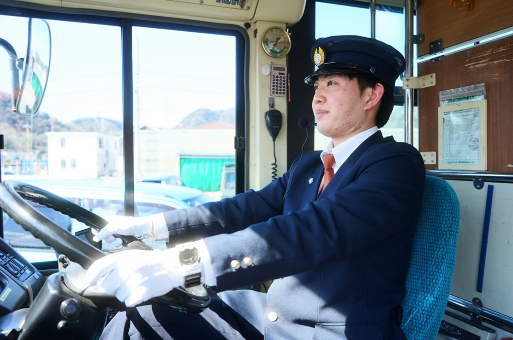 清潔で機能的なバス運転手の制服を着て、誇らしげに運転席に座る女性運転手