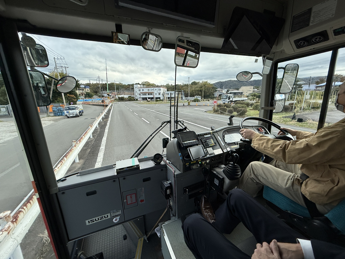 東海バスの敷地内で、実際のバスに乗り込む体験会参加者と、優しく指導するインストラクター