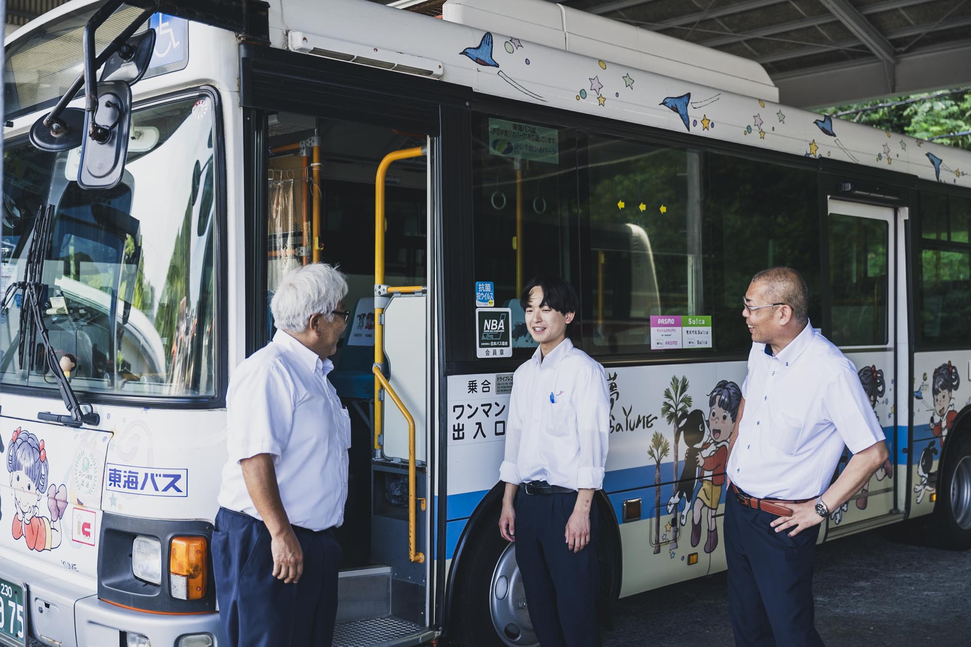 運転体験会の会場で、参加者に優しく説明をする女性スタッフと、興味深そうに聞く30代男性参加者