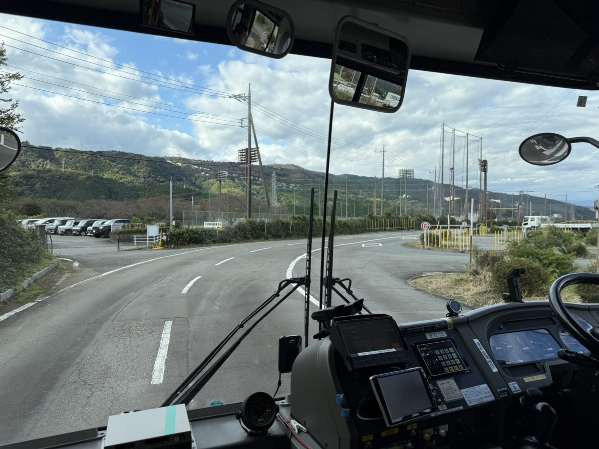 運転体験会で実際のバスの運転席に座って説明を受ける大学生