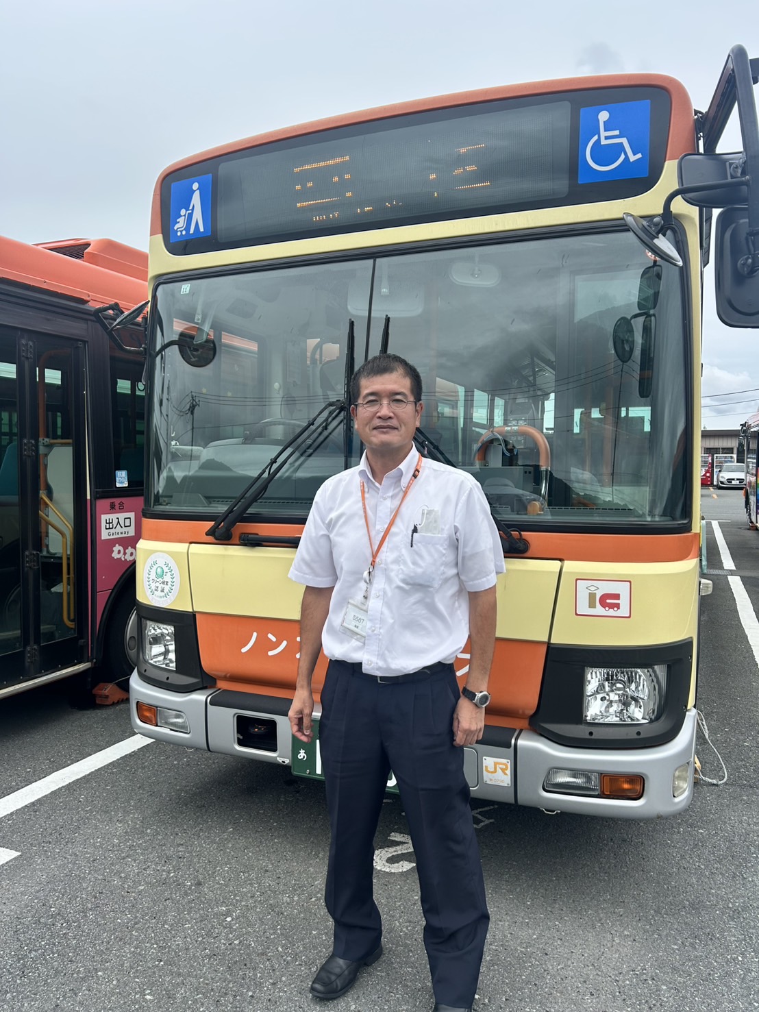 バスの前に立つ運転士の立ち姿。晴天の伊豆エリア、誠実で前向きな雰囲気