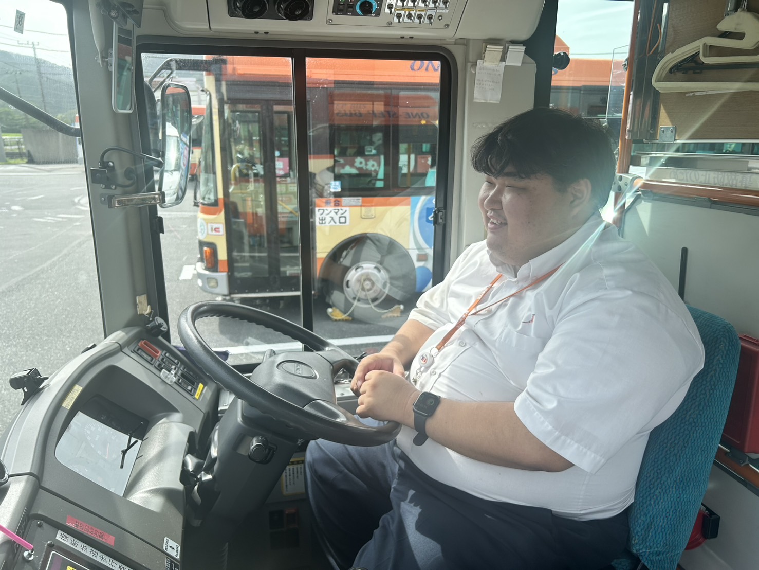 運転席でハンドルを握る運転士の男性、または終業時にバスの前で前向きな表情を見せる一枚