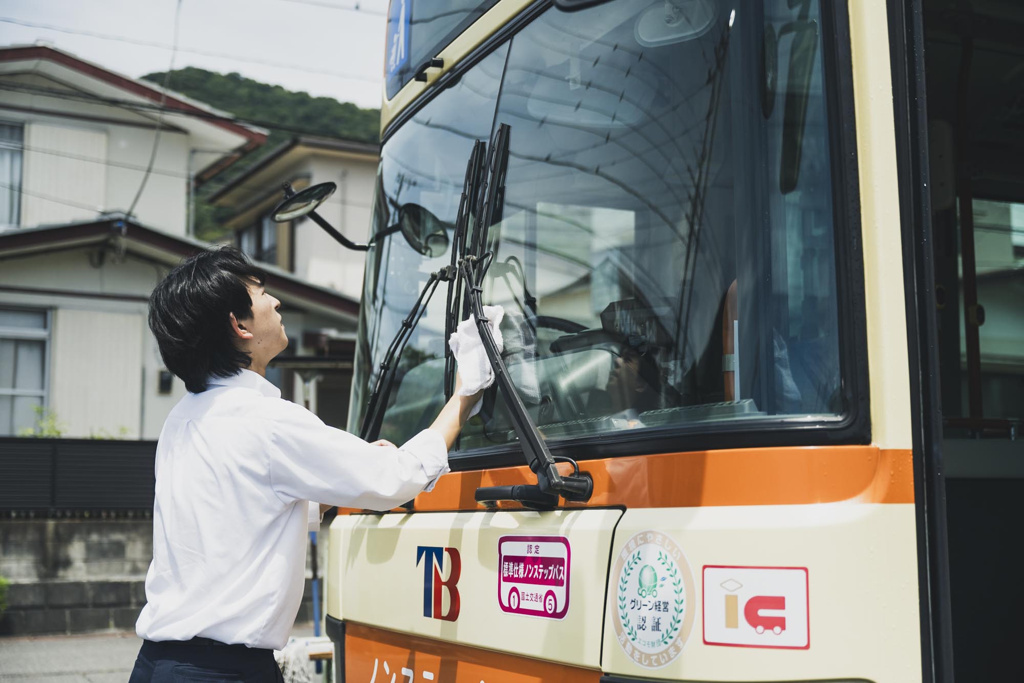制服を着て明るい表情でバス乗務前の準備をする運転士